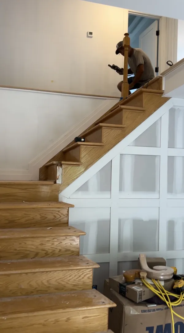 Oak staircase installation with white picture-frame wainscoting