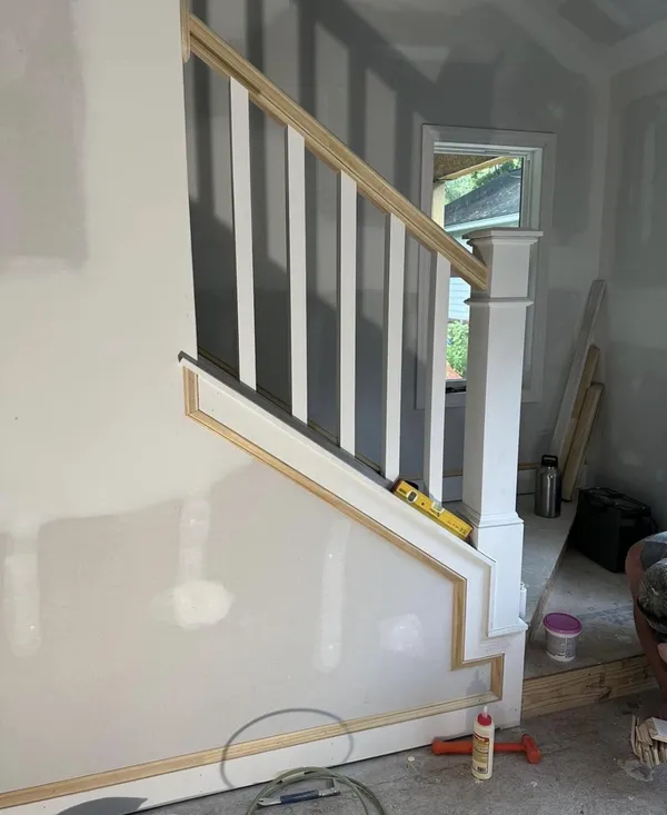 Staircase half-wall with wood trim and railing in progress