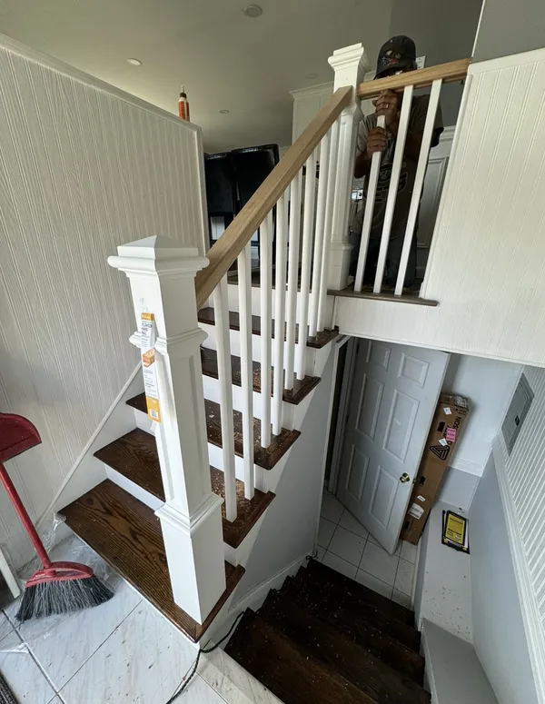 Refinished staircase with white newel posts and balusters in a split-level foyer