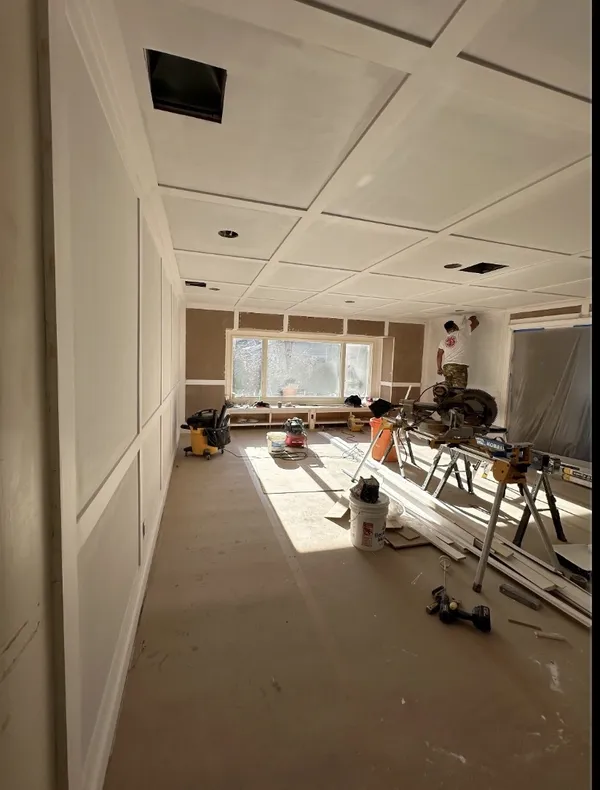 Room with coffered ceiling and picture-frame wainscoting under construction