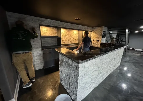 Basement bar under construction with stacked stone and granite top