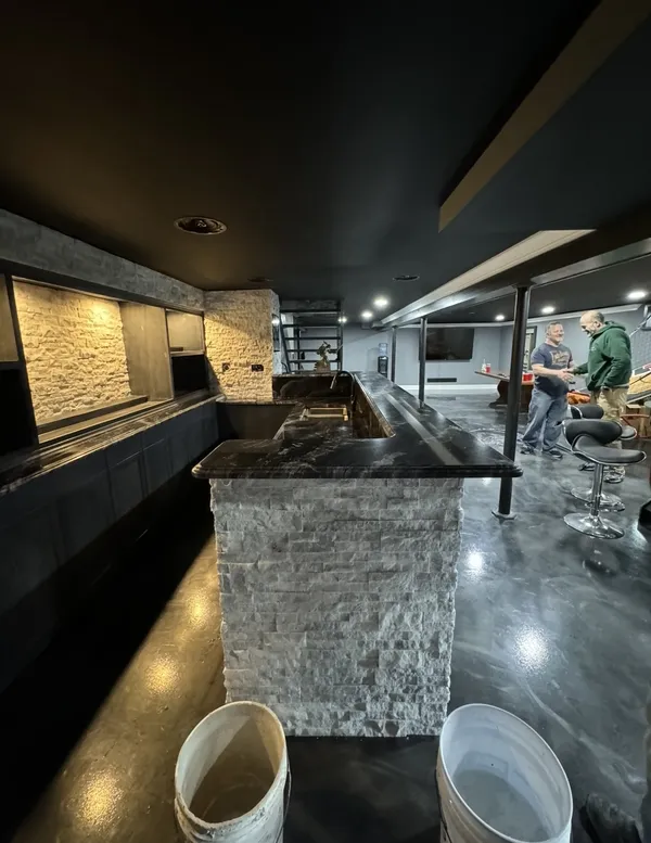 Basement entertainment bar with stacked stone and metallic epoxy floor