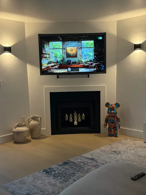 Remodeled corner fireplace with mounted TV and accent sconces