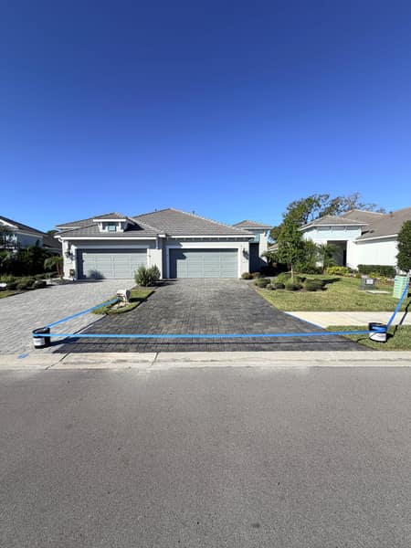 Paver driveway being pressure washed at a home exterior