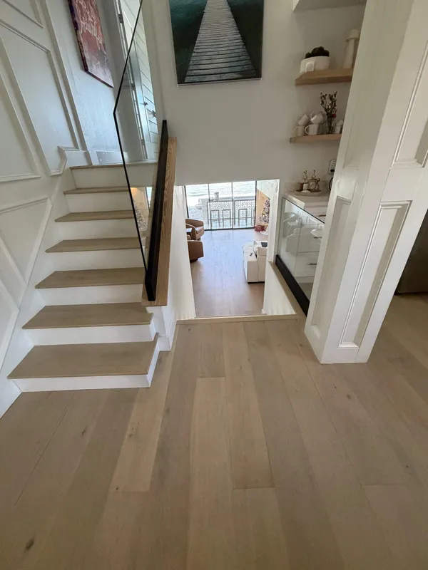 Staircase remodel with white oak treads, glass railing, and panel molding