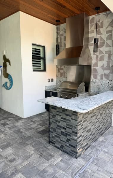 Custom outdoor kitchen with stone bar and tile backsplash