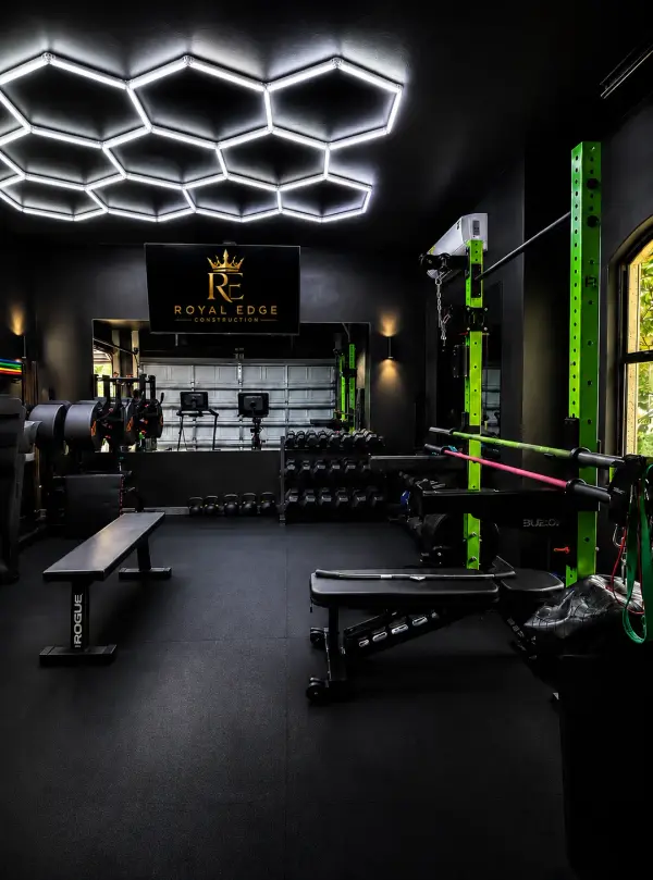 Black home gym renovation with hex LED lighting, mirrored wall and green squat rack