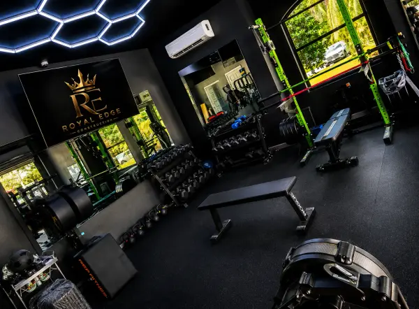 Home gym with wall-mounted TV, mirrored dumbbell area and flat bench