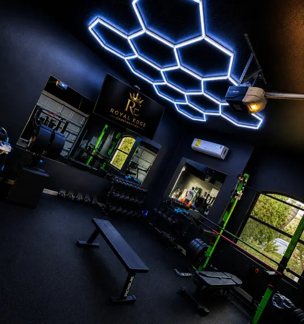 Converted garage gym with hexagon ceiling lighting, benches and power rack