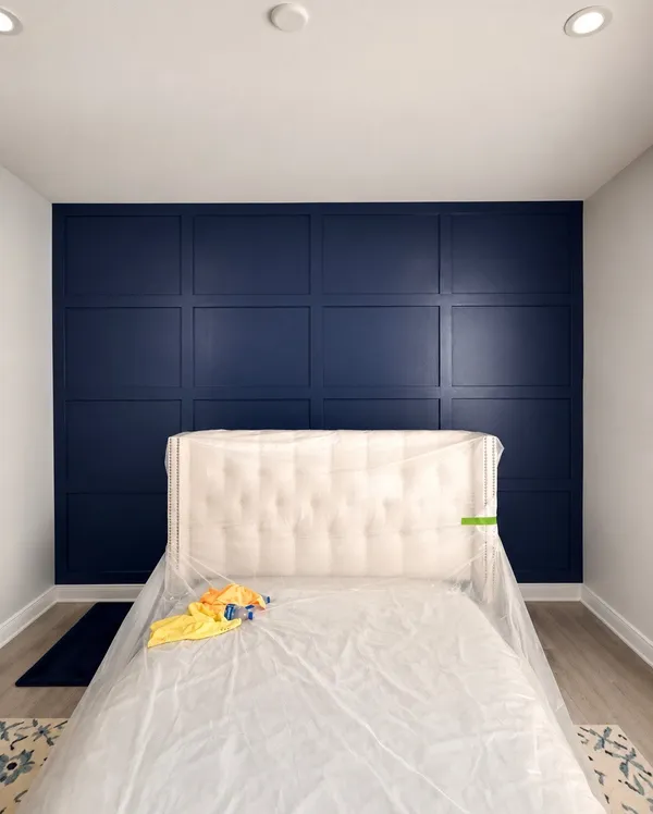Navy blue grid-panel board-and-batten accent wall behind a bedroom bed